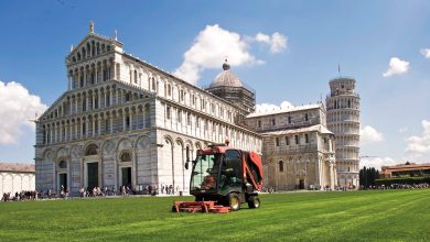 Groundskeeper mowing lawn near the Leaning Tower of Pisa and Pisa Cathedral in Italy